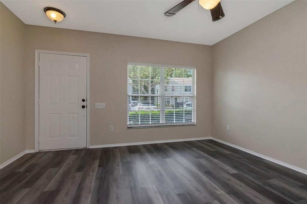 An empty room features beige walls, dark wood-look flooring, a ceiling fan, and a window — 2439 LAKE WOODBERRY CIRCLE, BRANDON, FL