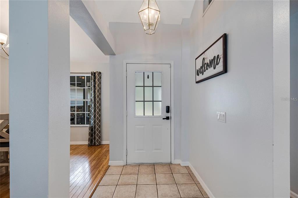 An entryway features a white front door, a geometric pendant light, and tiled flooring — 2305 JESSICA LANE, KISSIMMEE, FL