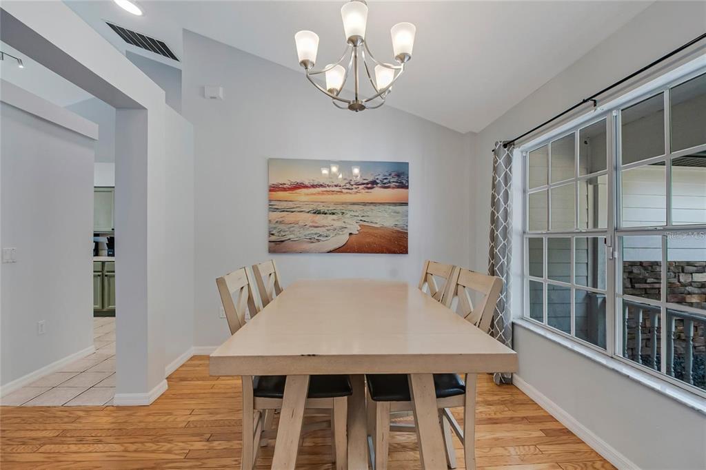 A dining room features a light-colored wooden table, four chairs, and a beach wall print — 2305 JESSICA LANE, KISSIMMEE, FL