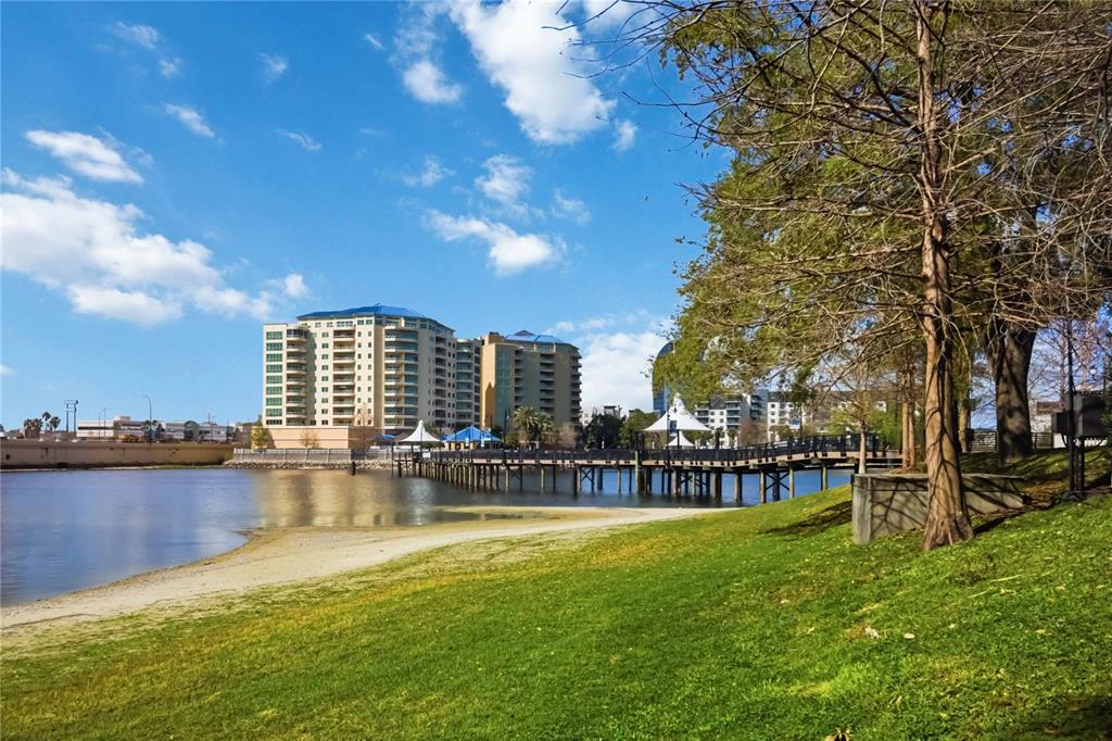 A wooden pedestrian bridge extends over a lake toward buildings under a blue sky — 127 OYSTER BAY CIRCLE UNIT 110, ALTAMONTE SPRINGS, FL
