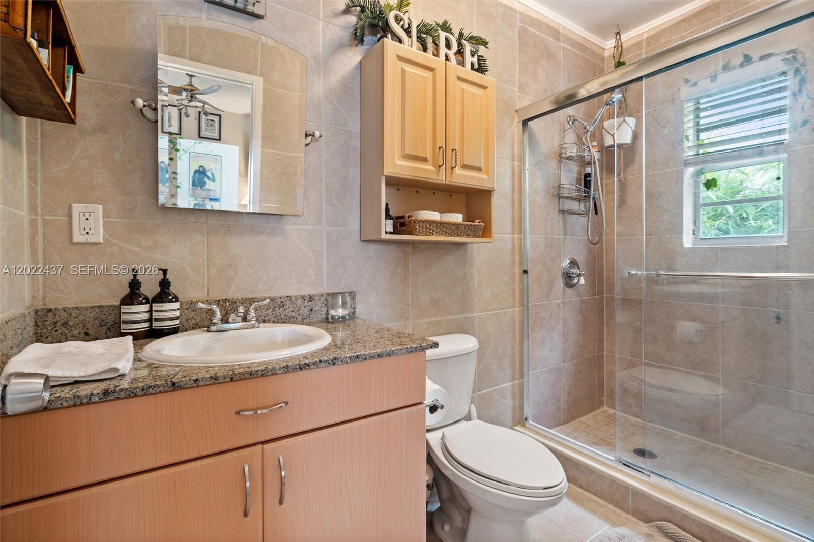A bathroom features a vanity with a granite countertop, a toilet, and a glass-enclosed shower — 936 Pennsylvania Ave # 205, Miami Beach FL 33139, MIAMI BEACH, FL