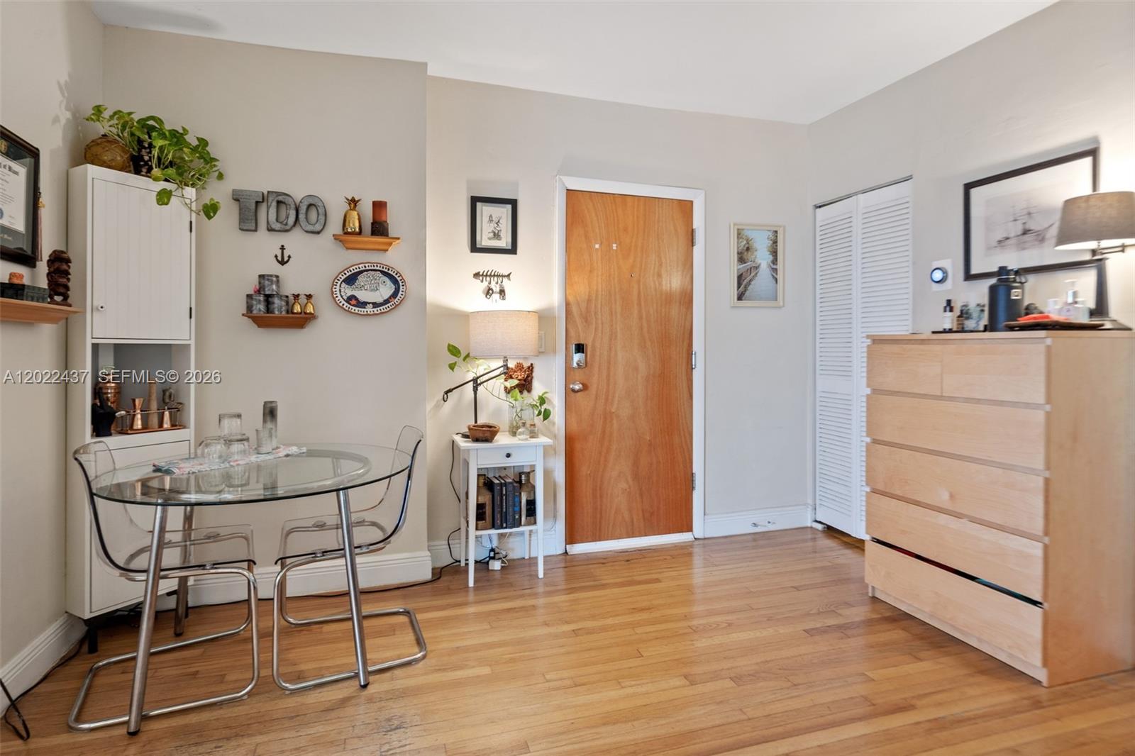 A dining area with a glass table, clear chairs, and a wooden door — 936 Pennsylvania Ave # 205, Miami Beach FL 33139, MIAMI BEACH, FL