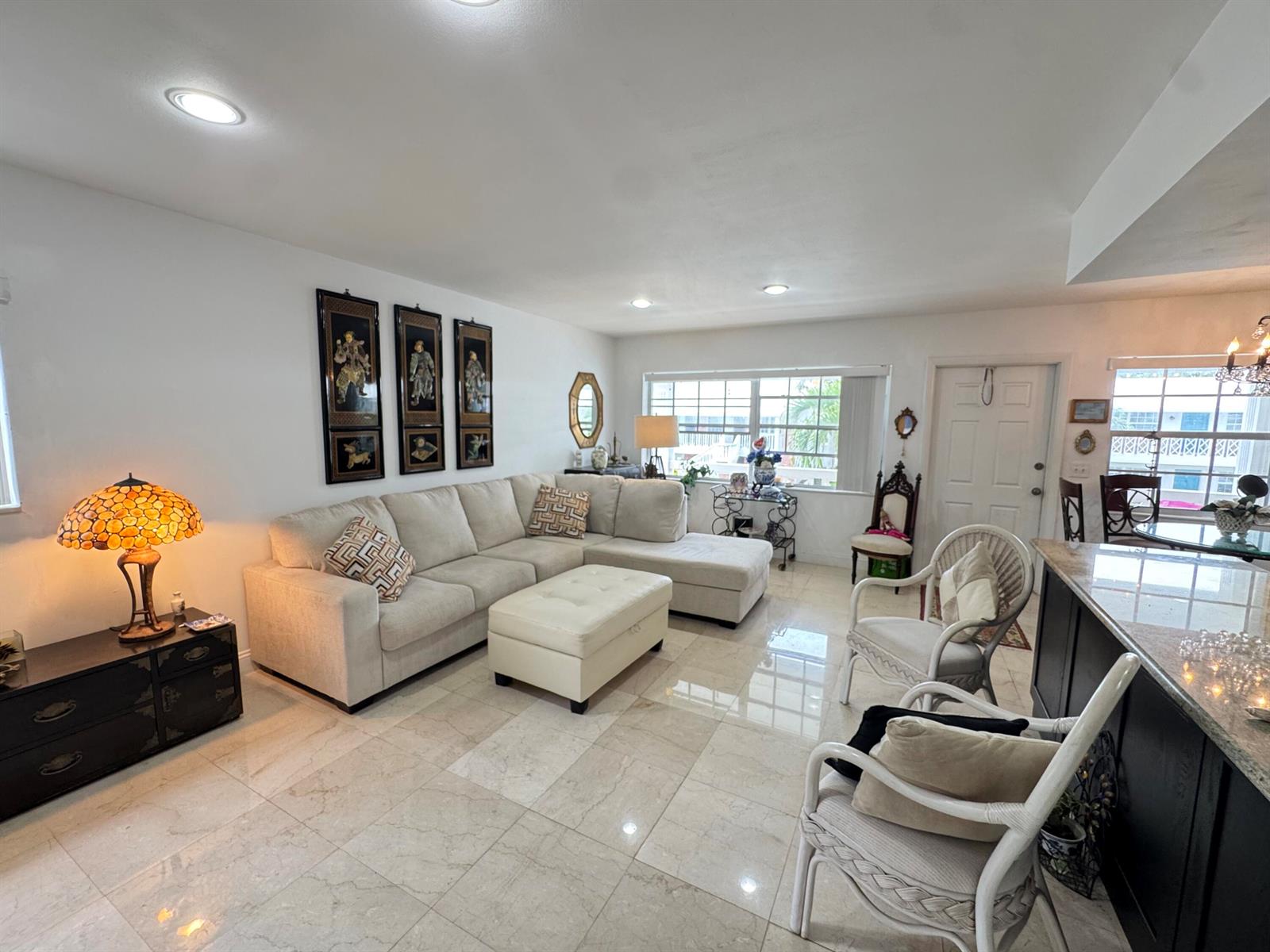 A living room features a beige sectional sofa, tile flooring, and a stained-glass lamp — 5505 N Ocean Boulevard # 203, Ocean Ridge FL 33435, OCEAN RIDGE, FL
