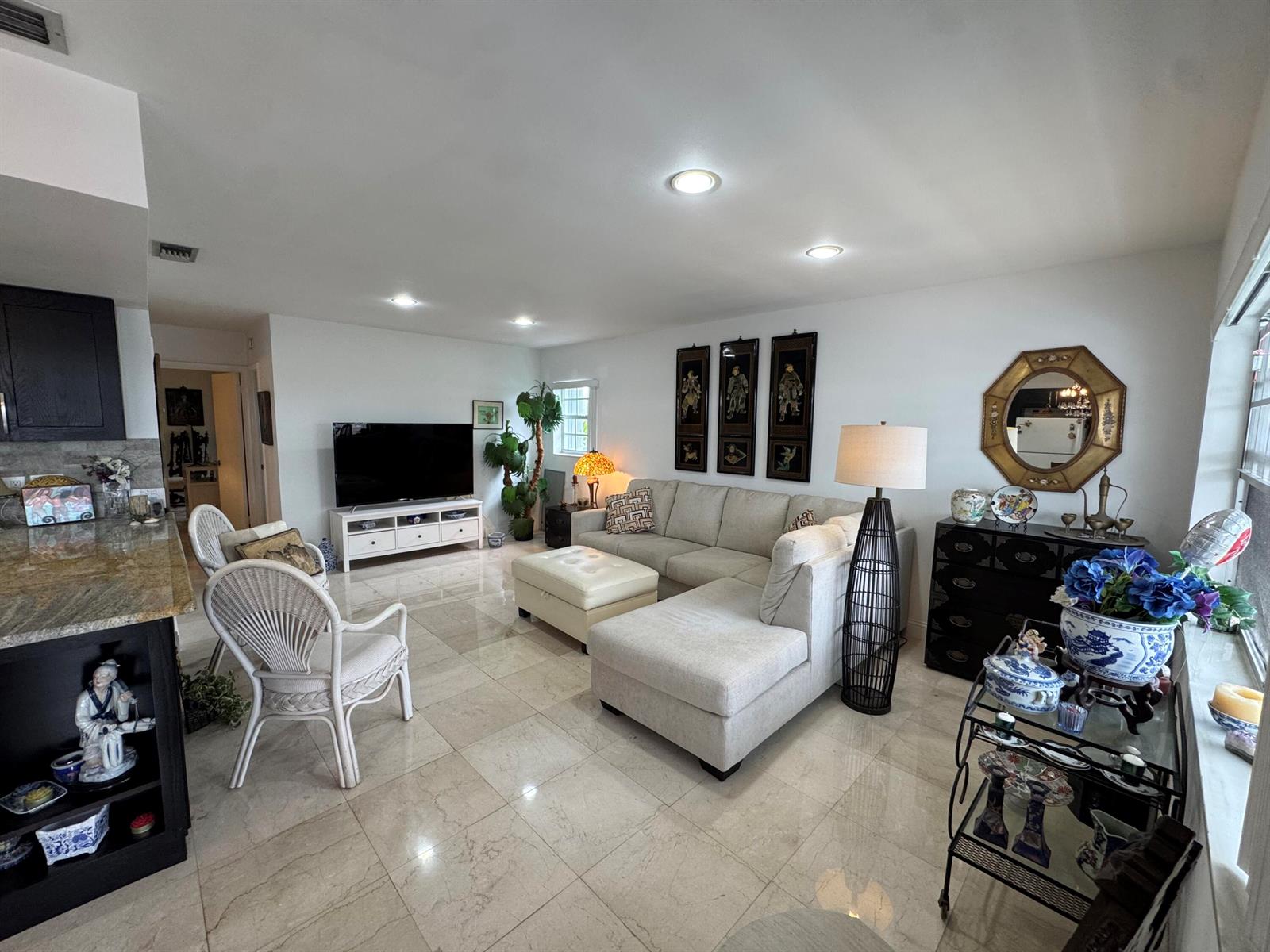 A living room features a sectional sofa, white wicker chairs, and light-colored tile flooring — 5505 N Ocean Boulevard # 203, Ocean Ridge FL 33435, OCEAN RIDGE, FL