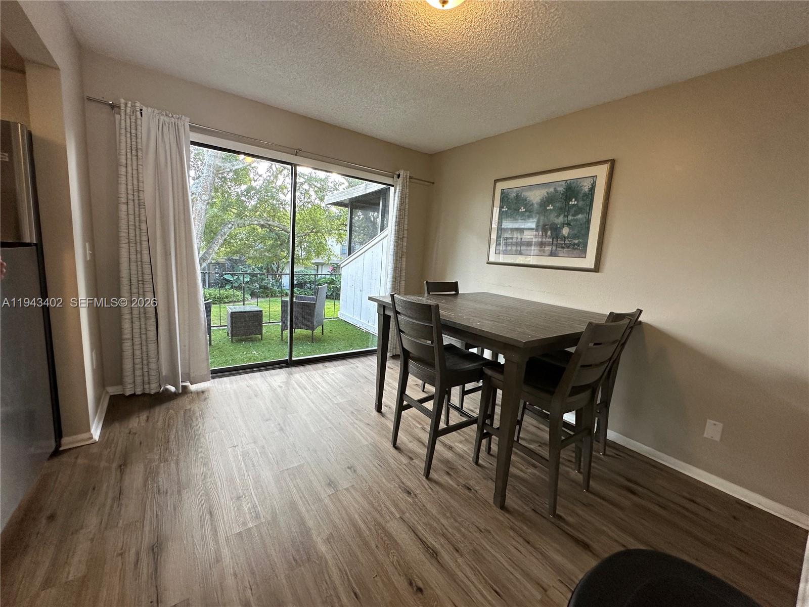 A dining area features wood-look flooring, a dark table with chairs, and a sliding glass door — 6060 Village Cir, Orlando FL 32822, ORLANDO, FL