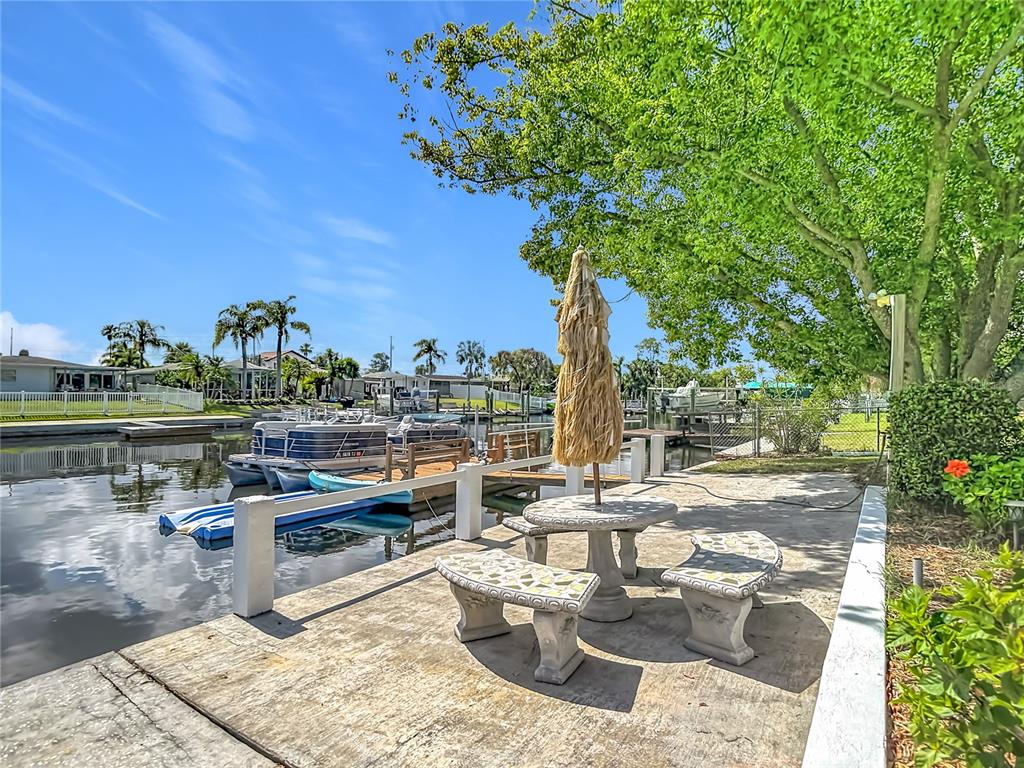 A concrete patio with a stone table and benches overlooks a canal with docked boats — 4237 HEADSAIL DRIVE, NEW PORT RICHEY, FL