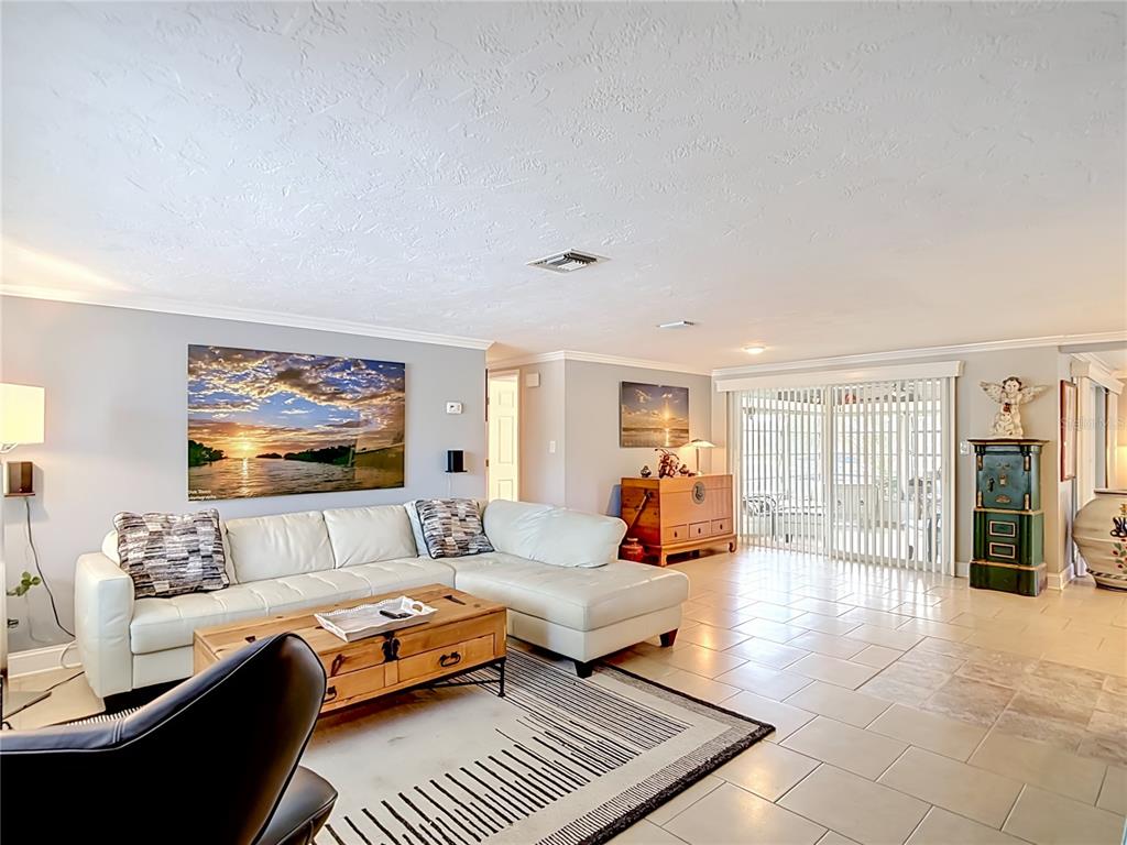 A living room features a white sectional sofa, a wooden coffee table, and tile flooring — 4237 HEADSAIL DRIVE, NEW PORT RICHEY, FL