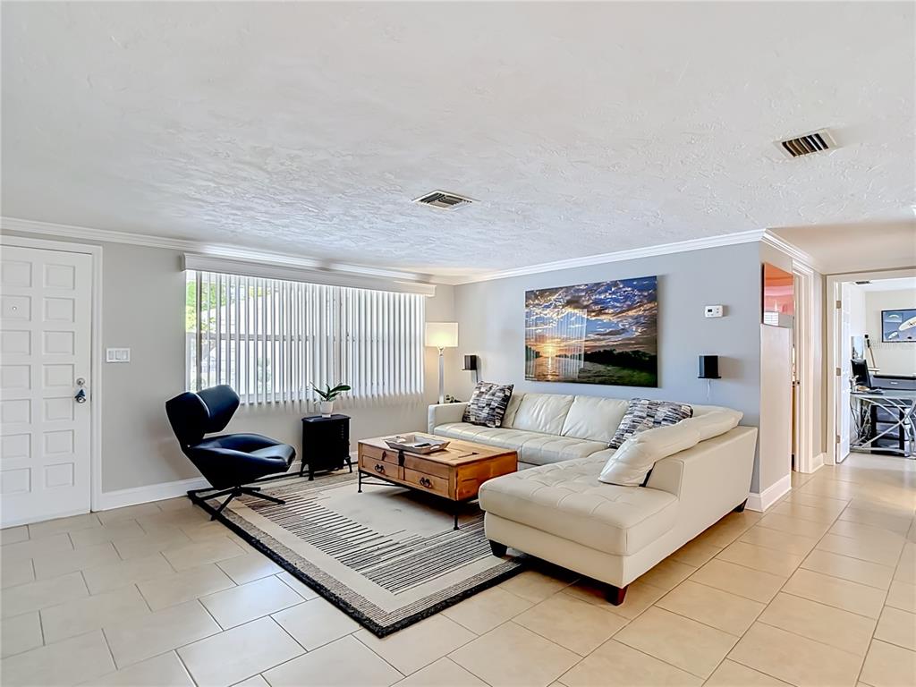 A living room features a white sectional sofa, a black lounge chair, and a wooden table — 4237 HEADSAIL DRIVE, NEW PORT RICHEY, FL