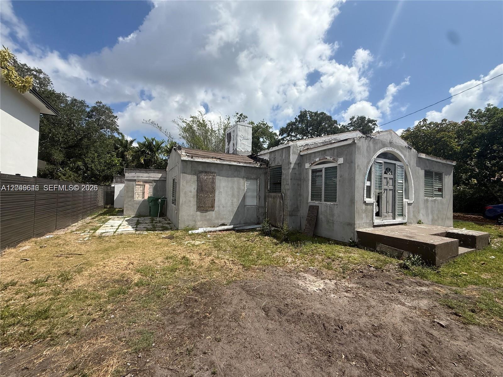 A weathered, single-story stucco house with an arched entryway and a flat roof — 751 NE 70th St, Miami FL 33138, MIAMI, FL