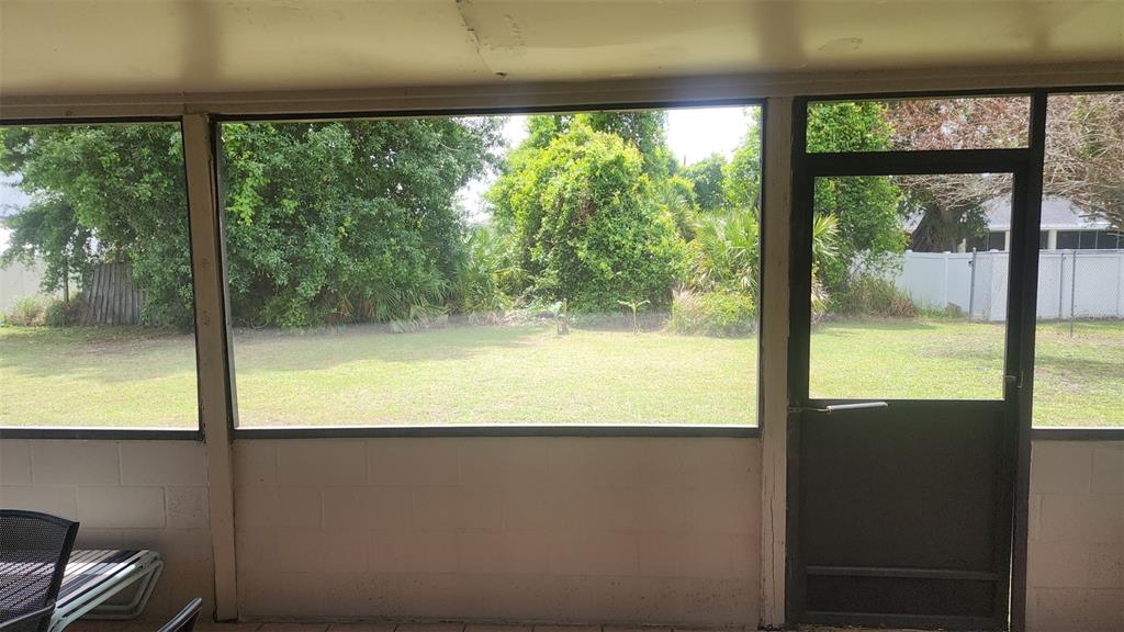 A screened-in porch overlooks a grassy backyard with trees and a white fence — 811 SAVONA PLACE, KISSIMMEE, FL