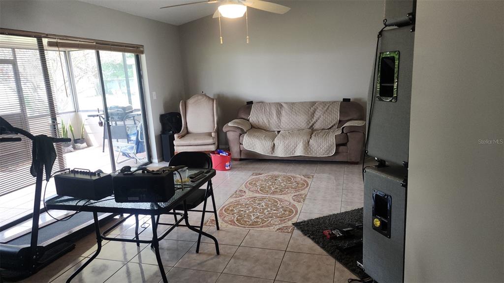 A living room with tile floors, a sofa, a dining table, and a ceiling fan — 811 SAVONA PLACE, KISSIMMEE, FL