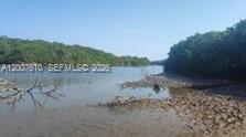 A view of a narrow waterway lined with dense green mangroves and a rocky shoreline — Zona Sur, Carretera del Litoral, Cangrejera, FL