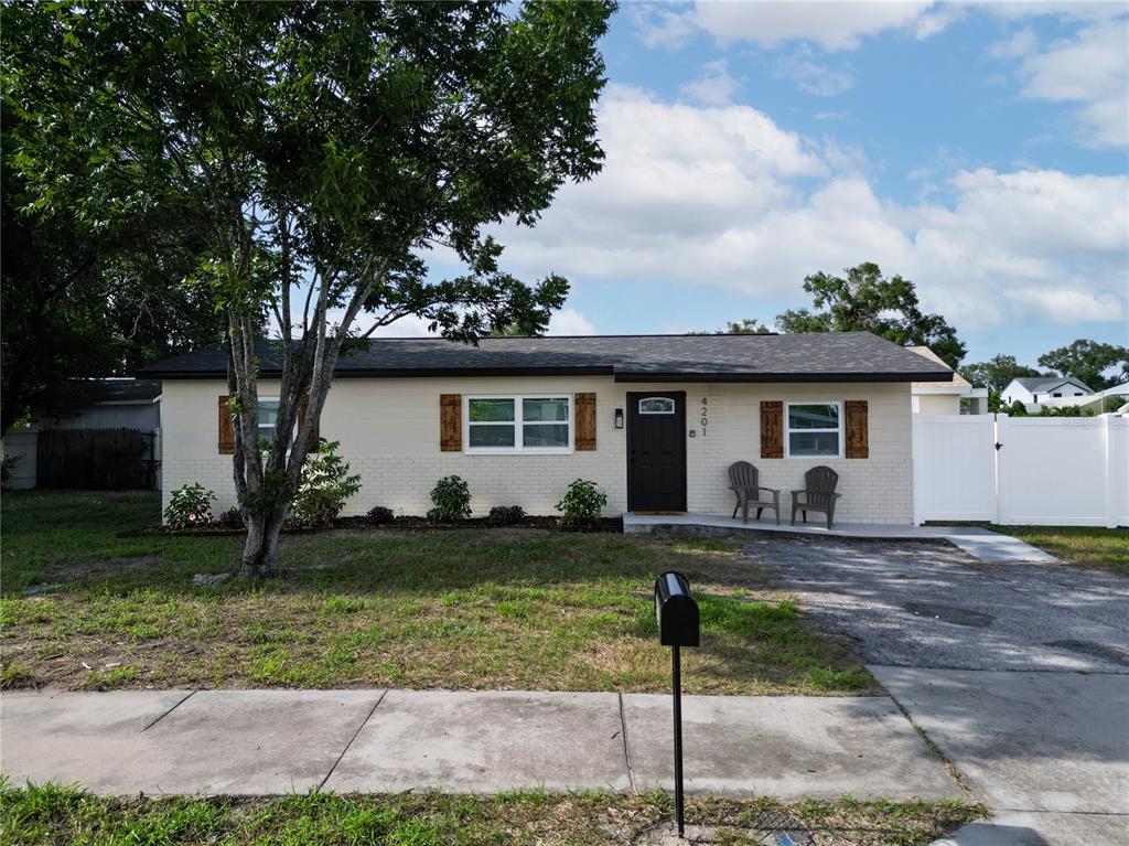 A single-story house with a light-colored brick exterior, dark shutters, and a black front door — 4201 55TH AVENUE N, ST PETERSBURG, FL