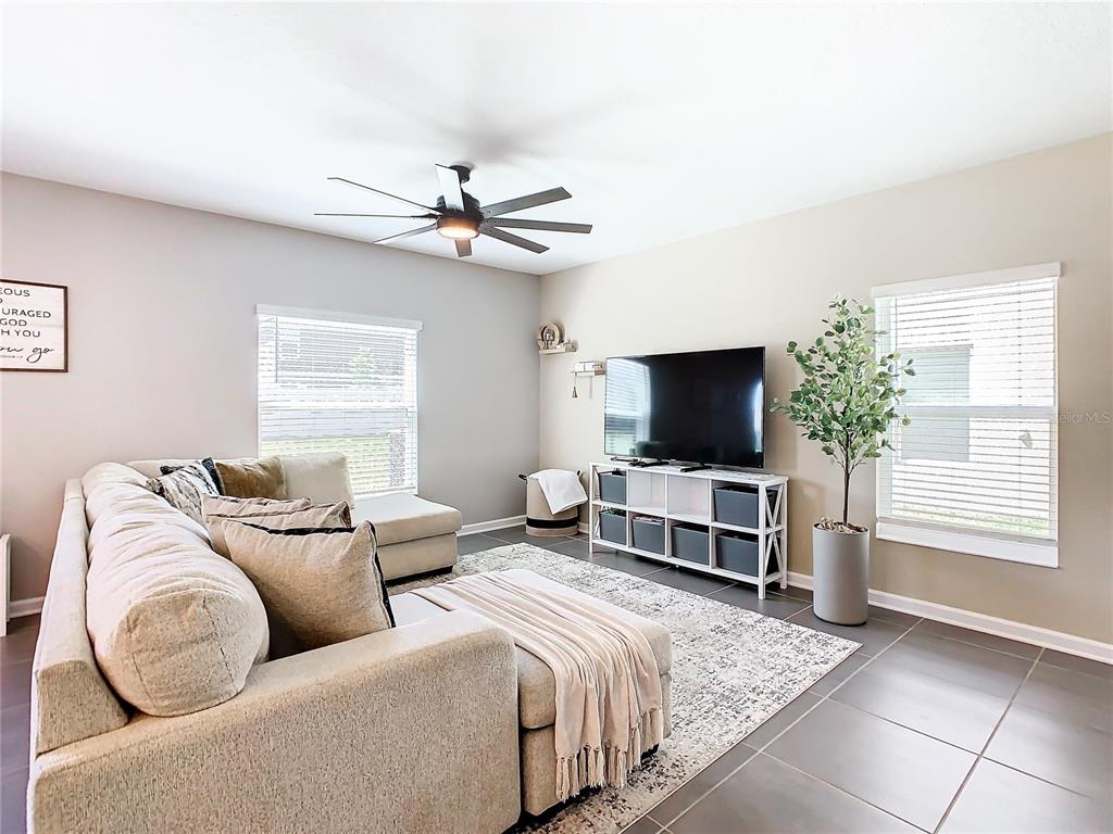 A living room features a sectional sofa, a television on a storage unit, and tile flooring — 1042 JOHN JACOB ROAD, DAVENPORT, FL