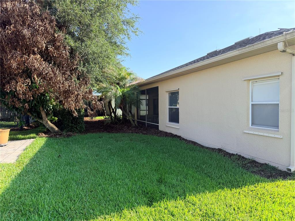 A side view of a house exterior with a lawn, a tree, and a screened-in porch — 941 SHOREHAVEN DRIVE, KISSIMMEE, FL