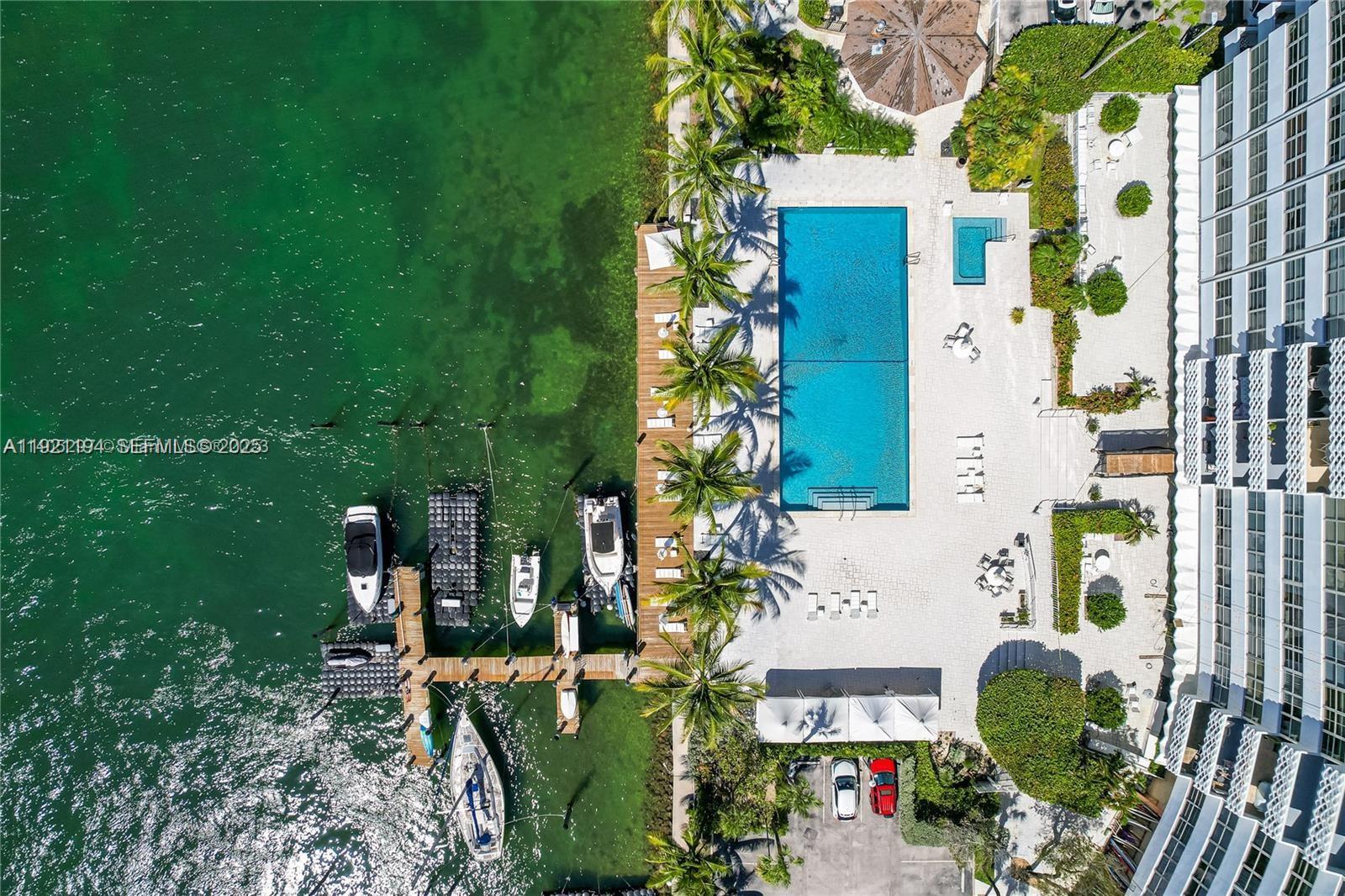 An aerial view shows a swimming pool, boat docks, and a building beside the water — 20 E Island Ave # 1415, Miami Beach FL 33139, MIAMI BEACH, FL