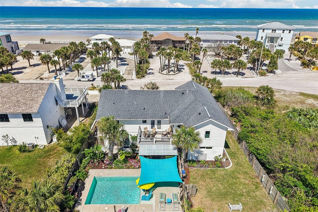 An aerial view shows a white house with a pool, patio, and oceanfront beach access — 4730 VAN KLEECK DRIVE, NEW SMYRNA BEACH, FL