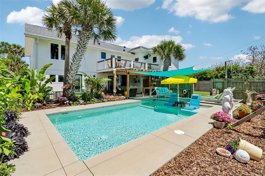 A backyard features a swimming pool with a sun shelf, a patio, and a two-story house — 4730 VAN KLEECK DRIVE, NEW SMYRNA BEACH, FL