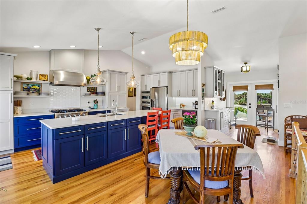 A kitchen with a blue island, white cabinets, and an adjacent dining area with wood floors — 4730 VAN KLEECK DRIVE, NEW SMYRNA BEACH, FL