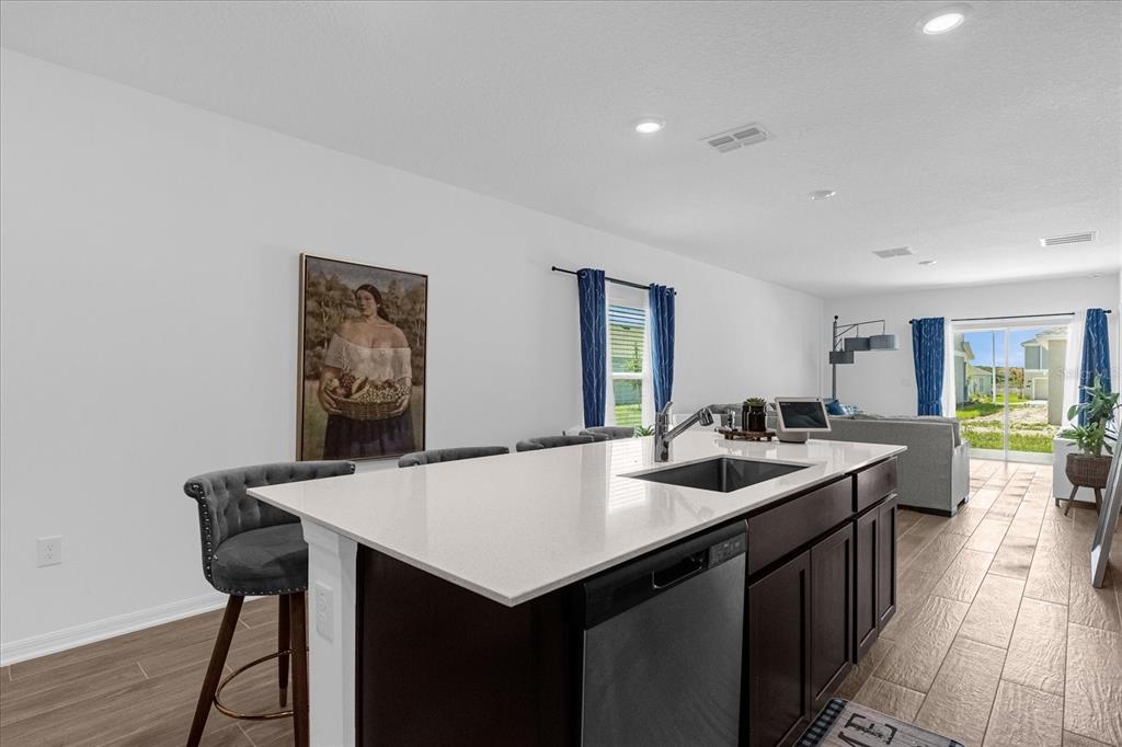 A kitchen island with a sink and bar seating sits in an open-concept living space — 622 BELL PRAIRIE CIRCLE, LAKE WALES, FL