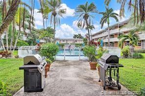 Two outdoor grills sit on a concrete patio in front of a swimming pool area — 141 NE 10th Ave # 29B, Hallandale Beach FL 33009, HALLANDALE BEACH, FL