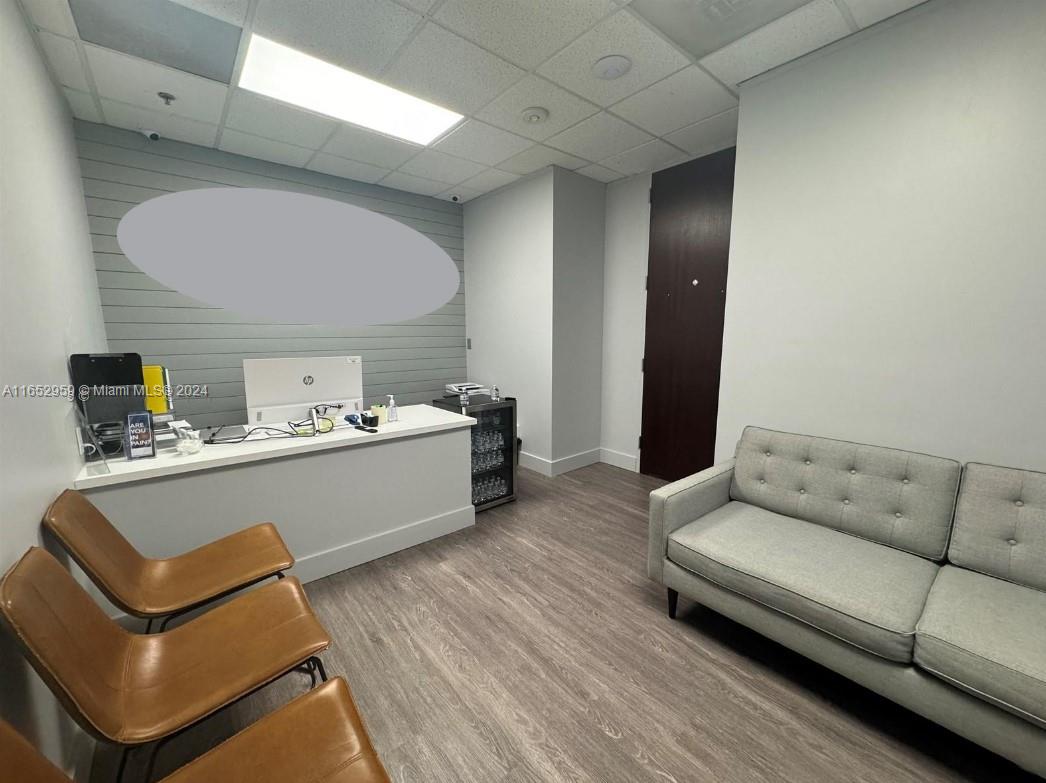An office space features a desk, two brown chairs, a gray sofa, and wood-look flooring — 9380 SW 150 Street # 210, FL 33176, FL