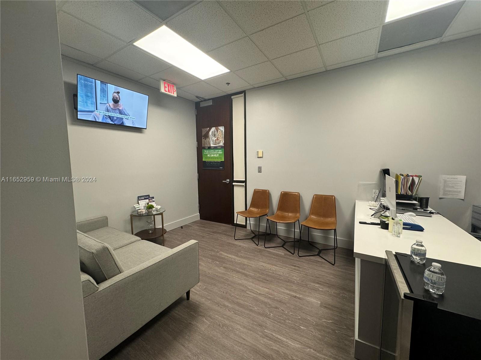 A waiting area features a grey sofa, three brown chairs, a desk, and a television — 9380 SW 150 Street # 210, FL 33176, FL