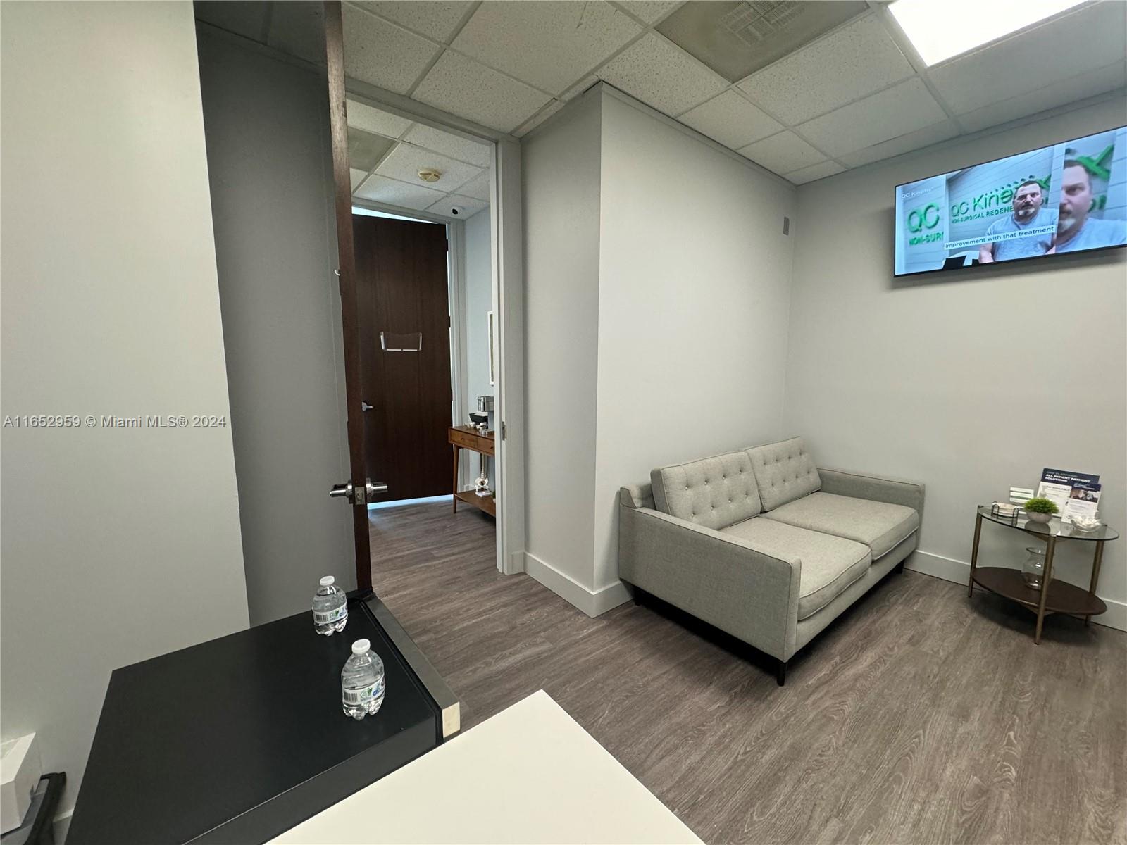 A waiting room features a gray sofa, a side table, and a wall-mounted television — 9380 SW 150 Street # 210, FL 33176, FL