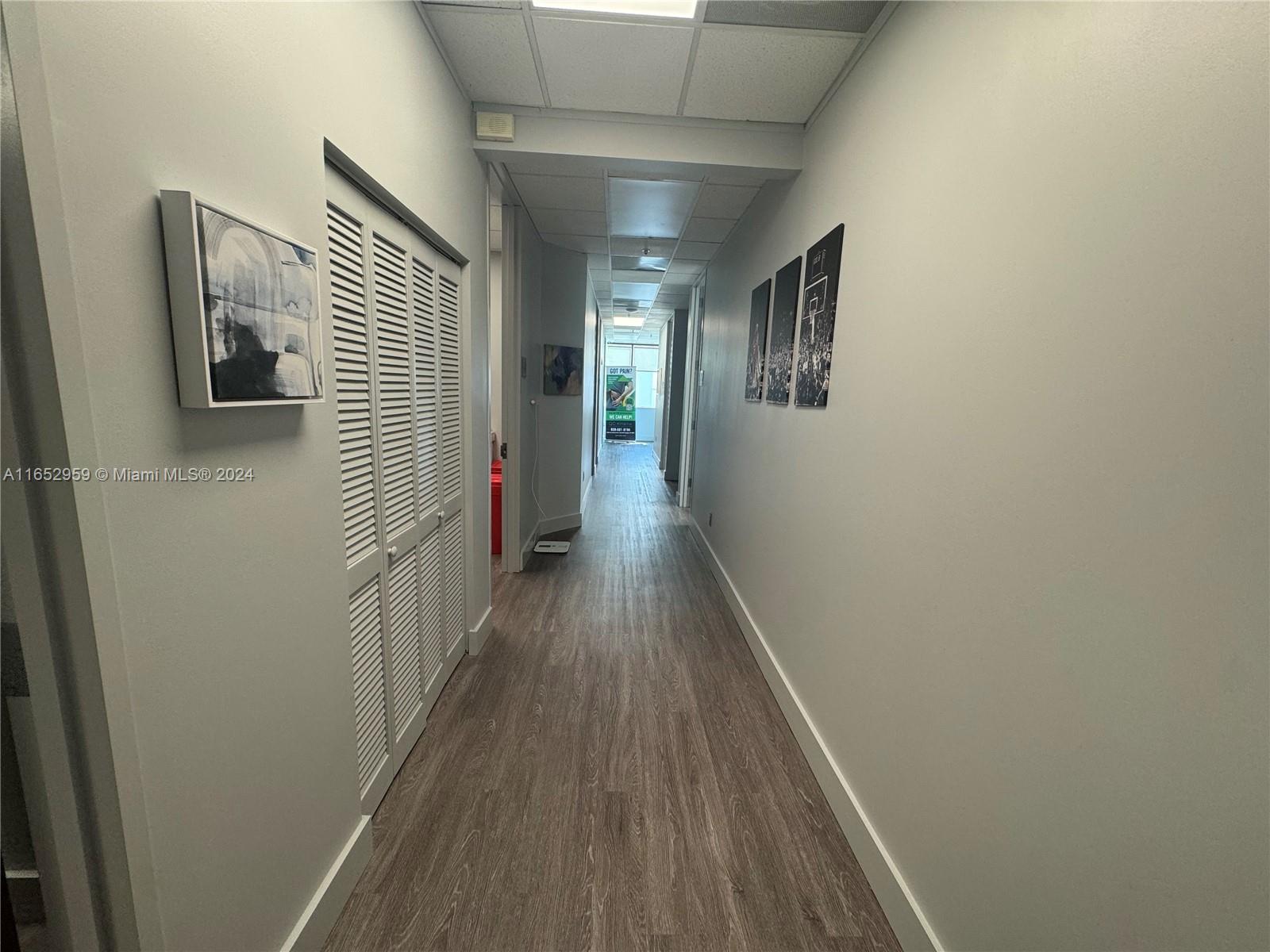 A long hallway features wood-look flooring, white walls, louvered closet doors, and drop ceiling tiles — 9380 SW 150 Street # 210, FL 33176, FL