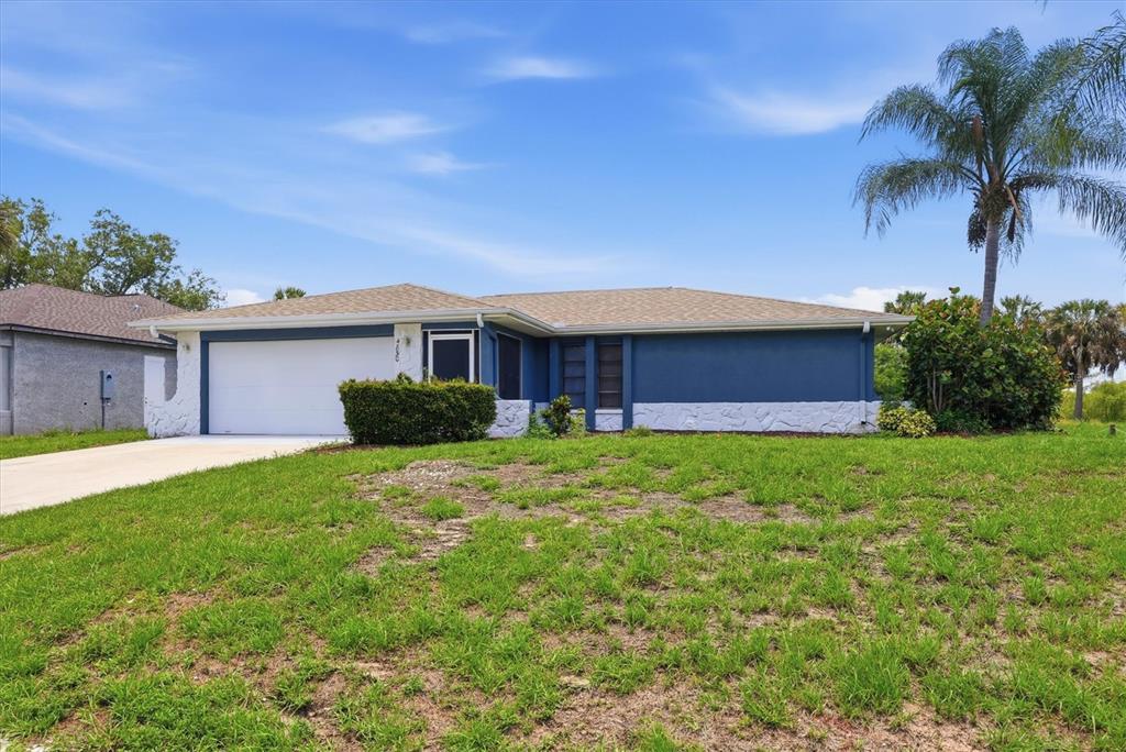 A single-story house with blue siding, a white stone base, and a two-car garage — 4850 BRICKELL DRIVE, NORTH PORT, FL