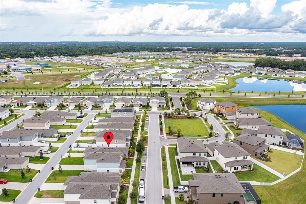 An aerial view shows a suburban neighborhood with houses, streets, and a nearby lake — 13011 PENNYBROOK DRIVE, RIVERVIEW, FL