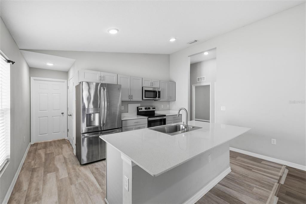 A kitchen features light gray cabinets, stainless steel appliances, and a white quartz island countertop — 13011 PENNYBROOK DRIVE, RIVERVIEW, FL