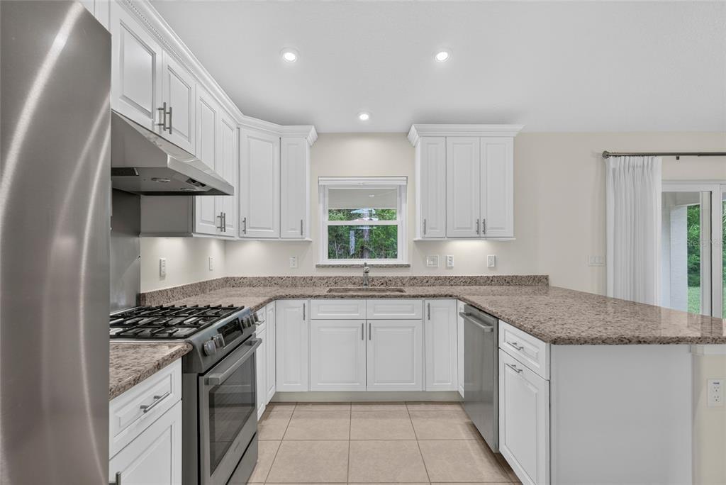 A kitchen with white cabinets, granite countertops, stainless steel appliances, and tile flooring — 39 WHITE HOUSE DRIVE, PALM COAST, FL