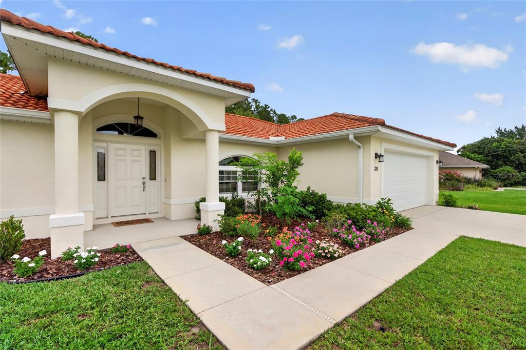 A single-story house with a tiled roof, arched entryway, and a landscaped front garden — 39 WHITE HOUSE DRIVE, PALM COAST, FL