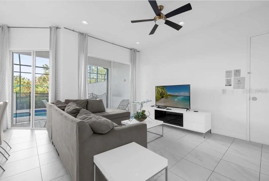 A living room with a grey sectional sofa, white media console, and sliding glass doors — 450 CAPTIVA DRIVE, DAVENPORT, FL