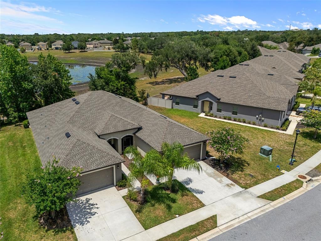 An aerial view shows two suburban houses with gray roofs and driveways near a pond — 14055 WEDDINGTON TERRACE, HUDSON, FL