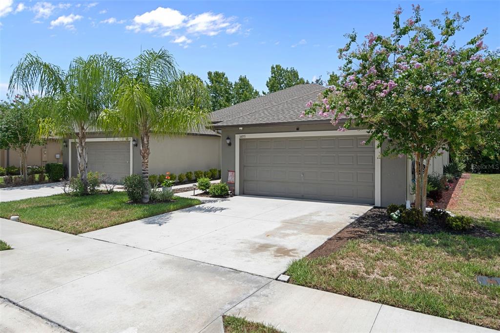A suburban house exterior features a two-car garage, a concrete driveway, and landscaped front yard — 14055 WEDDINGTON TERRACE, HUDSON, FL
