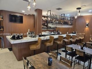 A bar area features a marble-topped counter, wooden slat walls, and hanging pendant lights — MIAMI SPRINGS, FL