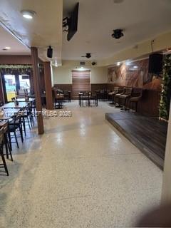 This interior view shows a restaurant or bar area with tables, chairs, and a raised stage — MIAMI SPRINGS, FL
