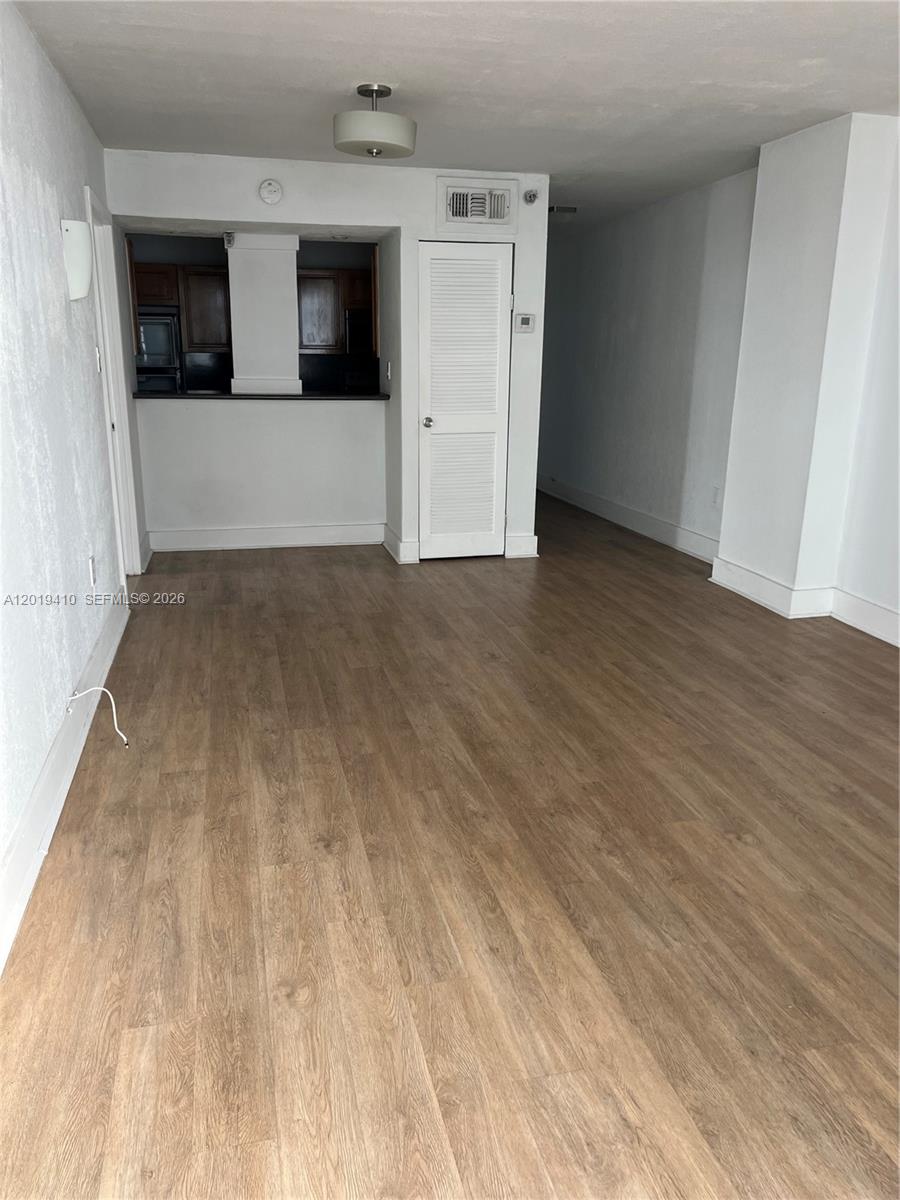 An interior view shows a living area with wood-look flooring, a kitchen pass-through, and a closet — NORTH BAY VILLAGE, FL