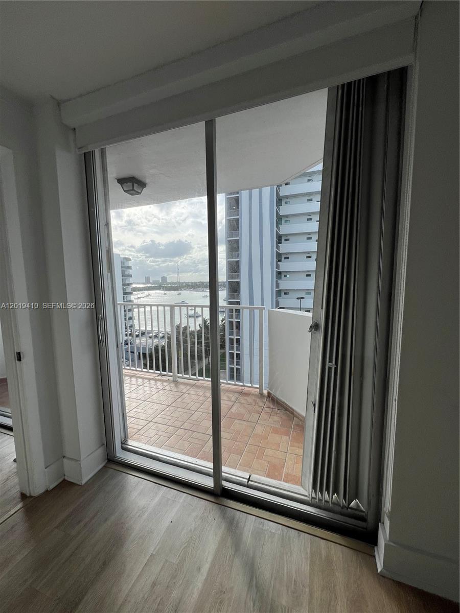 A sliding glass door opens onto a balcony overlooking a bay and nearby buildings — NORTH BAY VILLAGE, FL