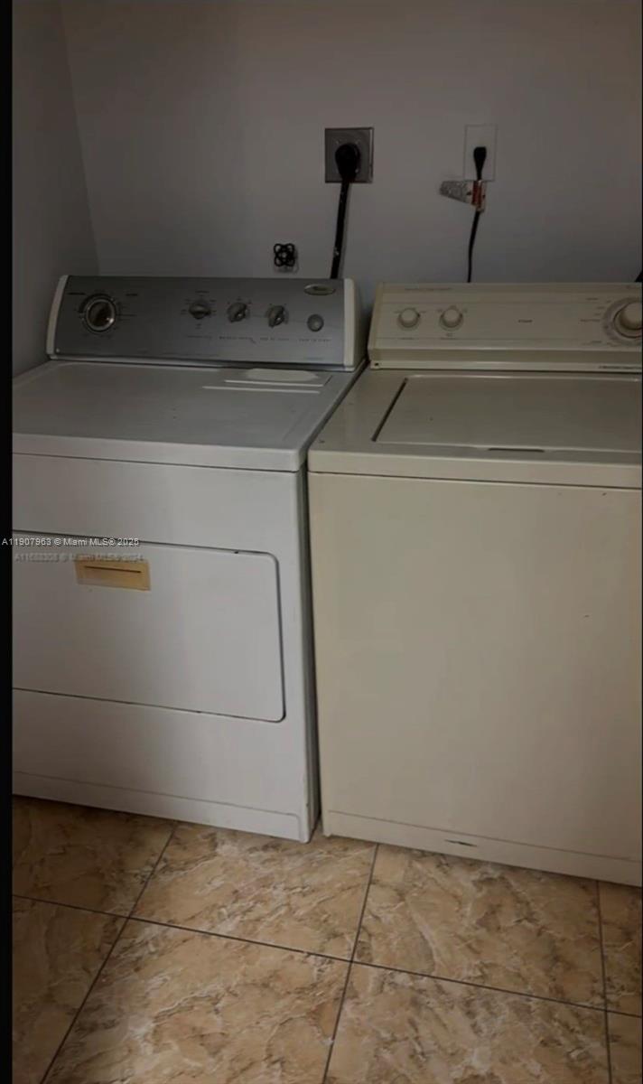 A white dryer and a beige washing machine sit side-by-side on a tiled floor — 2952 NW 55th Ave # 2D, Lauderhill FL 33313, LAUDERHILL, FL