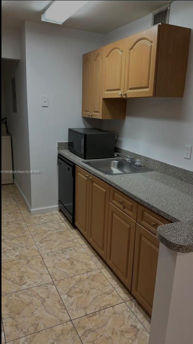 A kitchen features light wood cabinets, a gray speckled countertop, and a black dishwasher — 2952 NW 55th Ave # 2D, Lauderhill FL 33313, LAUDERHILL, FL