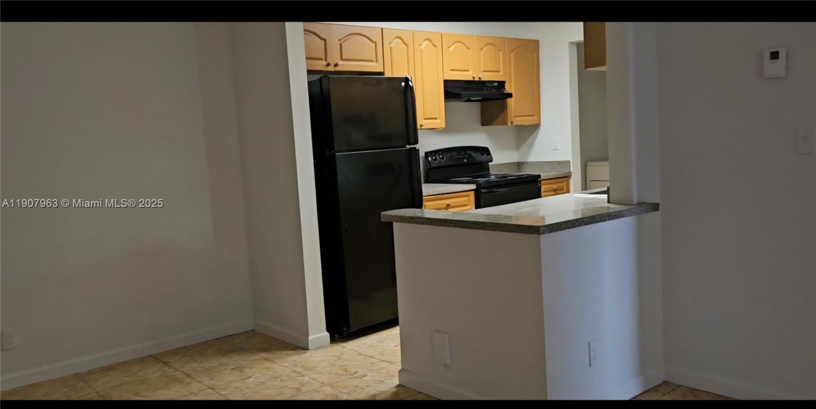 A kitchen features light wood cabinets, black appliances, and a granite-topped breakfast bar — 2952 NW 55th Ave # 2D, Lauderhill FL 33313, LAUDERHILL, FL