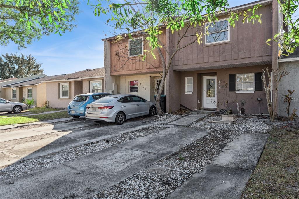 A two-story townhouse with a concrete driveway and two parked cars in front — 2538 RIO PINAR LAKES BOULEVARD, ORLANDO, FL
