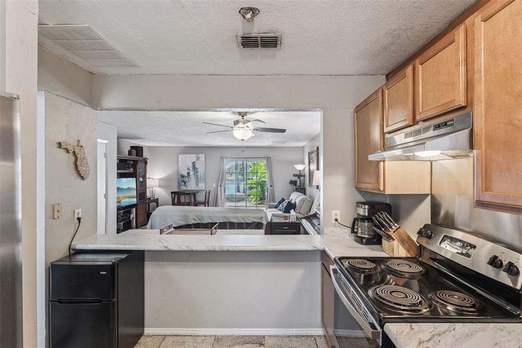 A kitchen with light wood cabinets and a pass-through window overlooking a living area — 2538 RIO PINAR LAKES BOULEVARD, ORLANDO, FL