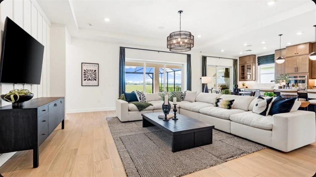 A spacious open-concept living room features a large sectional sofa, dark coffee table, and kitchen — 26625 DOVE DRIVE, PUNTA GORDA, FL