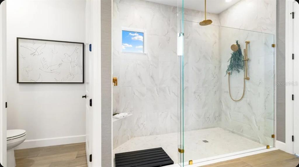 A bathroom features a glass-enclosed walk-in shower with marble-look tile and gold fixtures — 26625 DOVE DRIVE, PUNTA GORDA, FL
