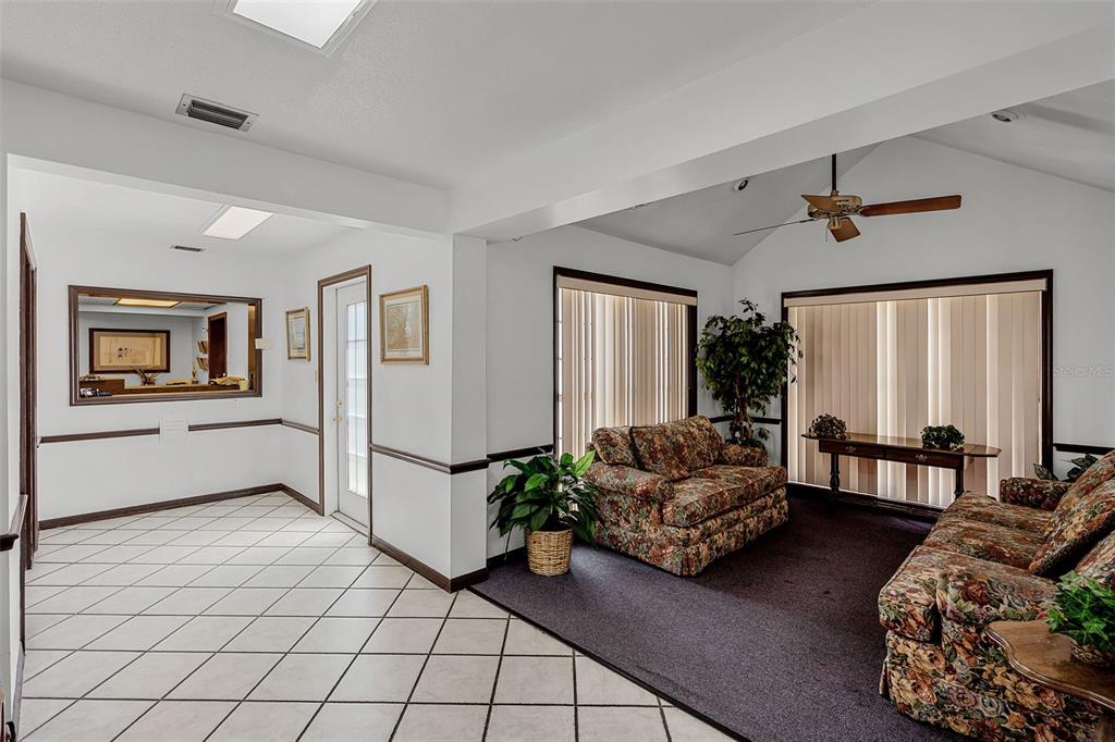 A living room with floral sofas, dark carpet, and an adjacent tiled entryway — 131 W MAIN STREET, TAVARES, FL