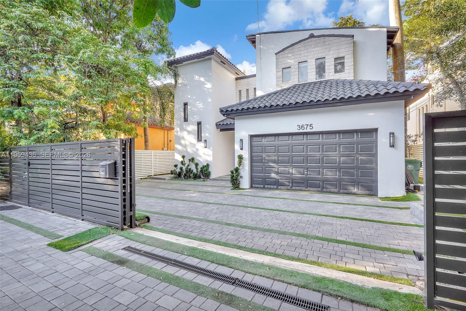 A two-story house with a gray garage, paved driveway, and a modern metal fence — 3675 Loquat Ave, Miami FL 33133, MIAMI, FL
